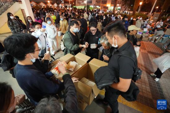 11月27日,义工在宏福苑附近向受火灾影响的市民派发物资。新华社发(吕小炜摄)